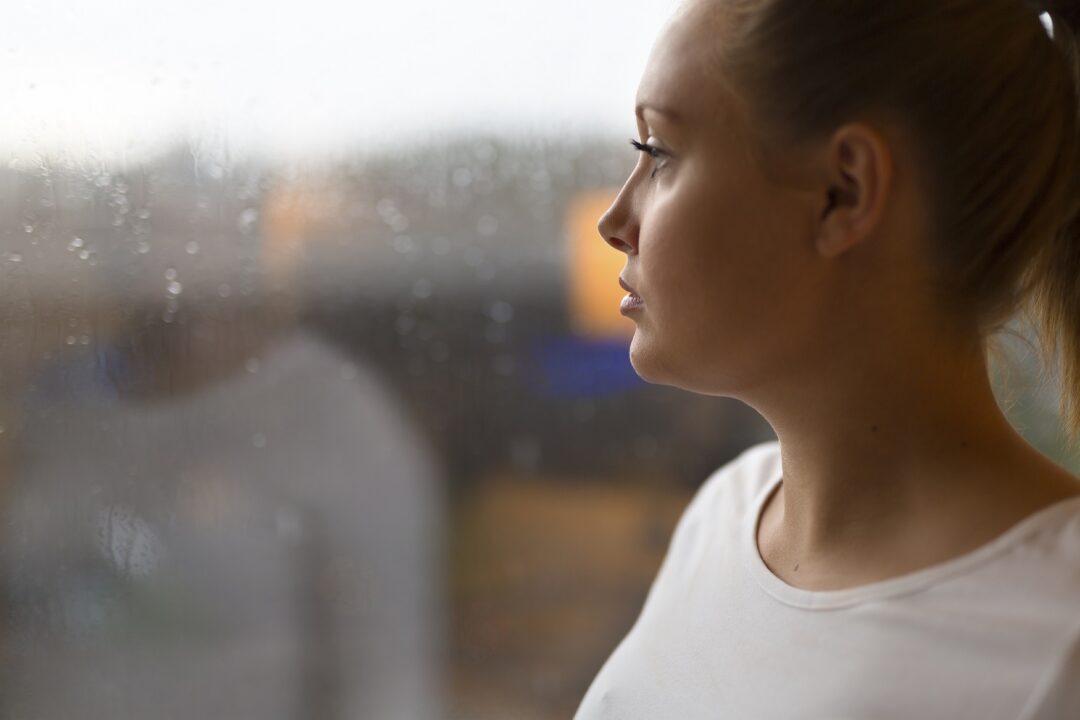 Kvinna med ångest och depression tittar ut genom fönstret