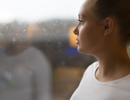 Kvinna med ångest och depression tittar ut genom fönstret